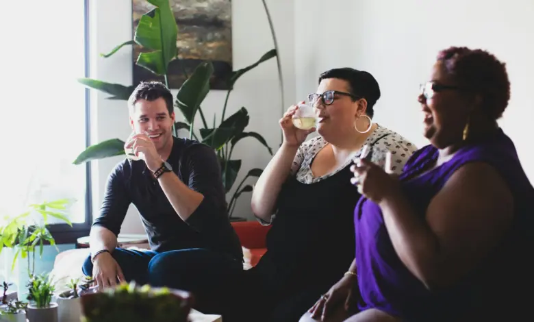 smiling one man and two women holding glasses