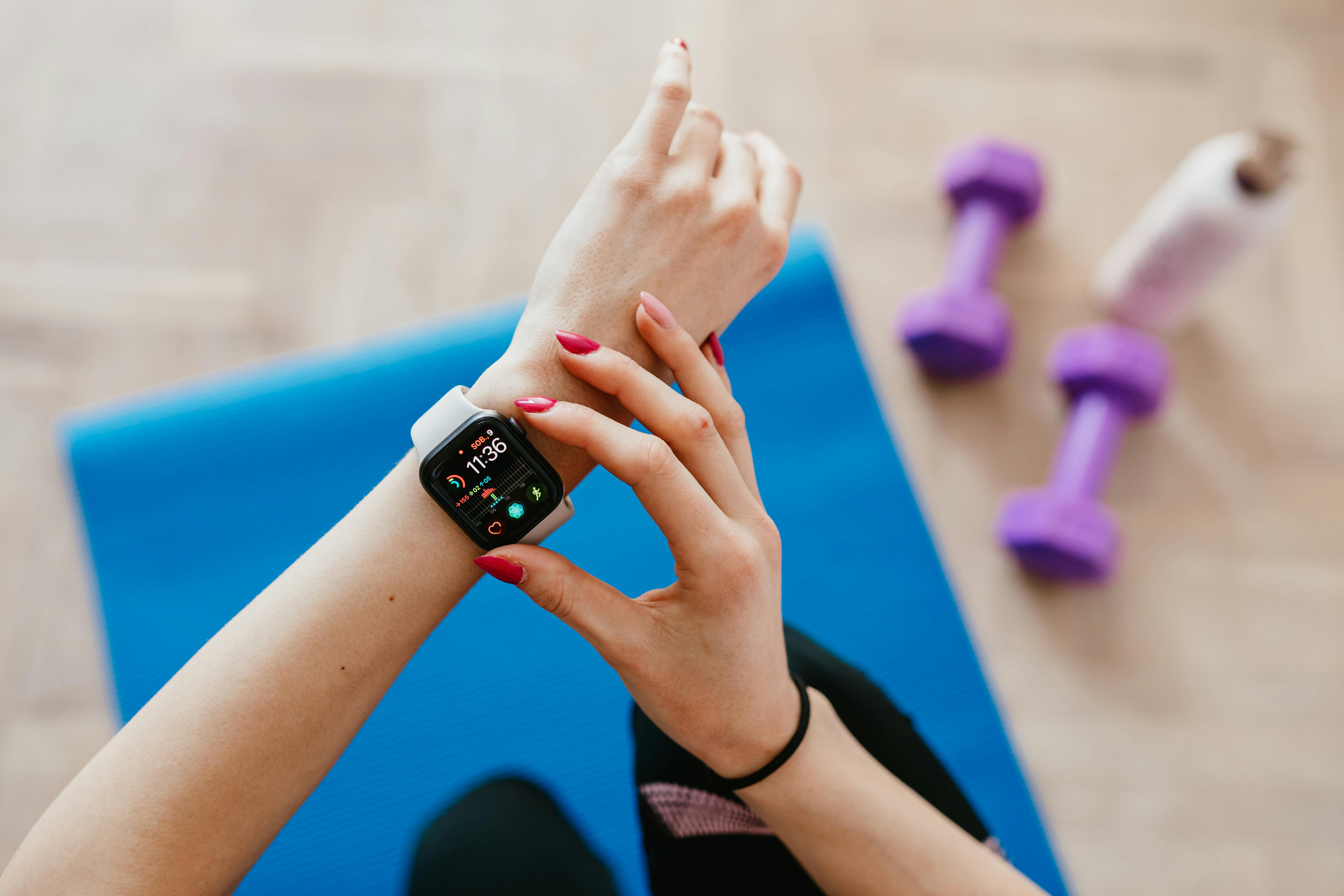 A woman checks fitness data on her smartwatch during a workout at home.